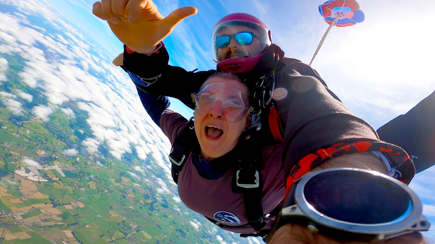 An image of a GGNWE member participating in a tandem skydive.